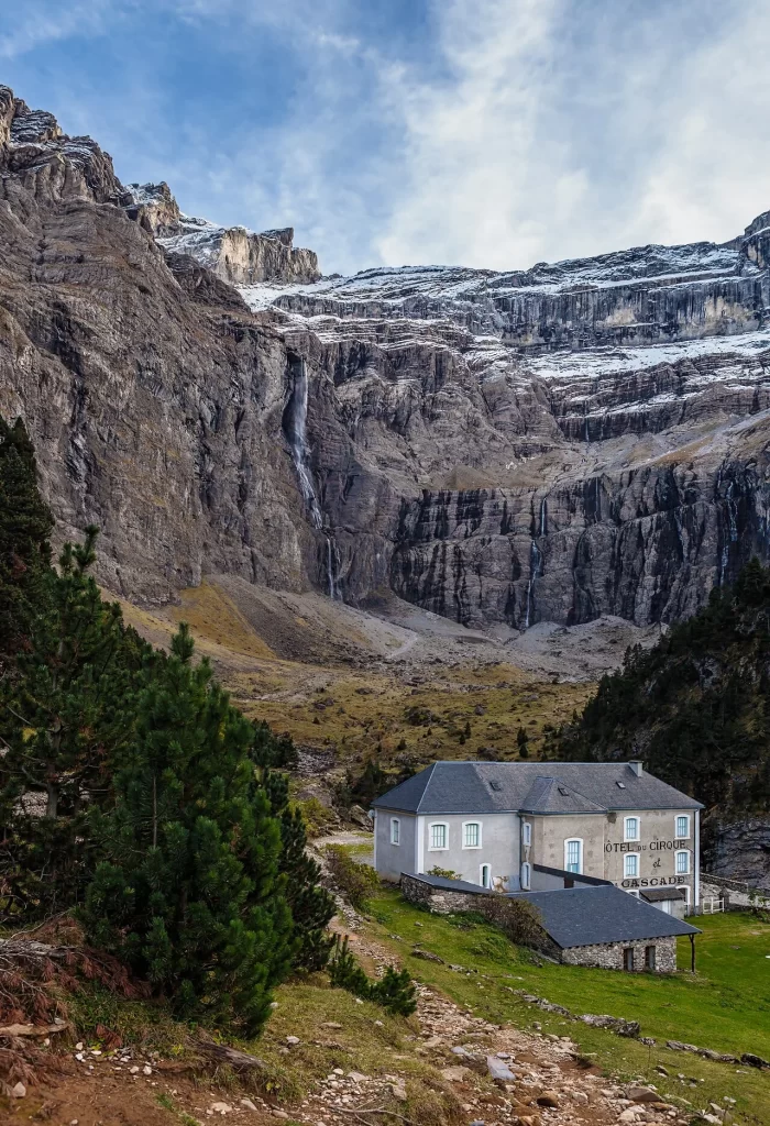 La Grande Cascade de Gavarnie tombant de la paroi enneigée du cirque, le bâtiment de l'Hôtel du Cirque et de la Cascade au premier plan
