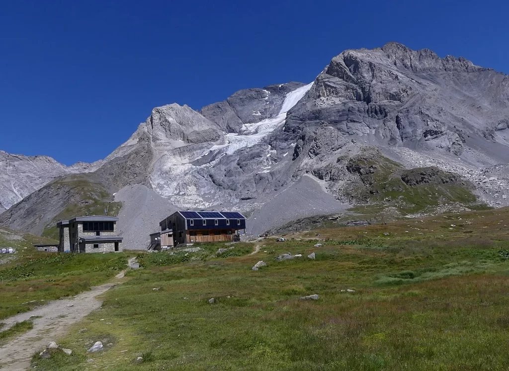 Refuge du col de la Vanoise, bâtiment en bois au toit solaire à côté d'un bâtiment en pierre, au pied de la Grande Casse et de ses glaciers